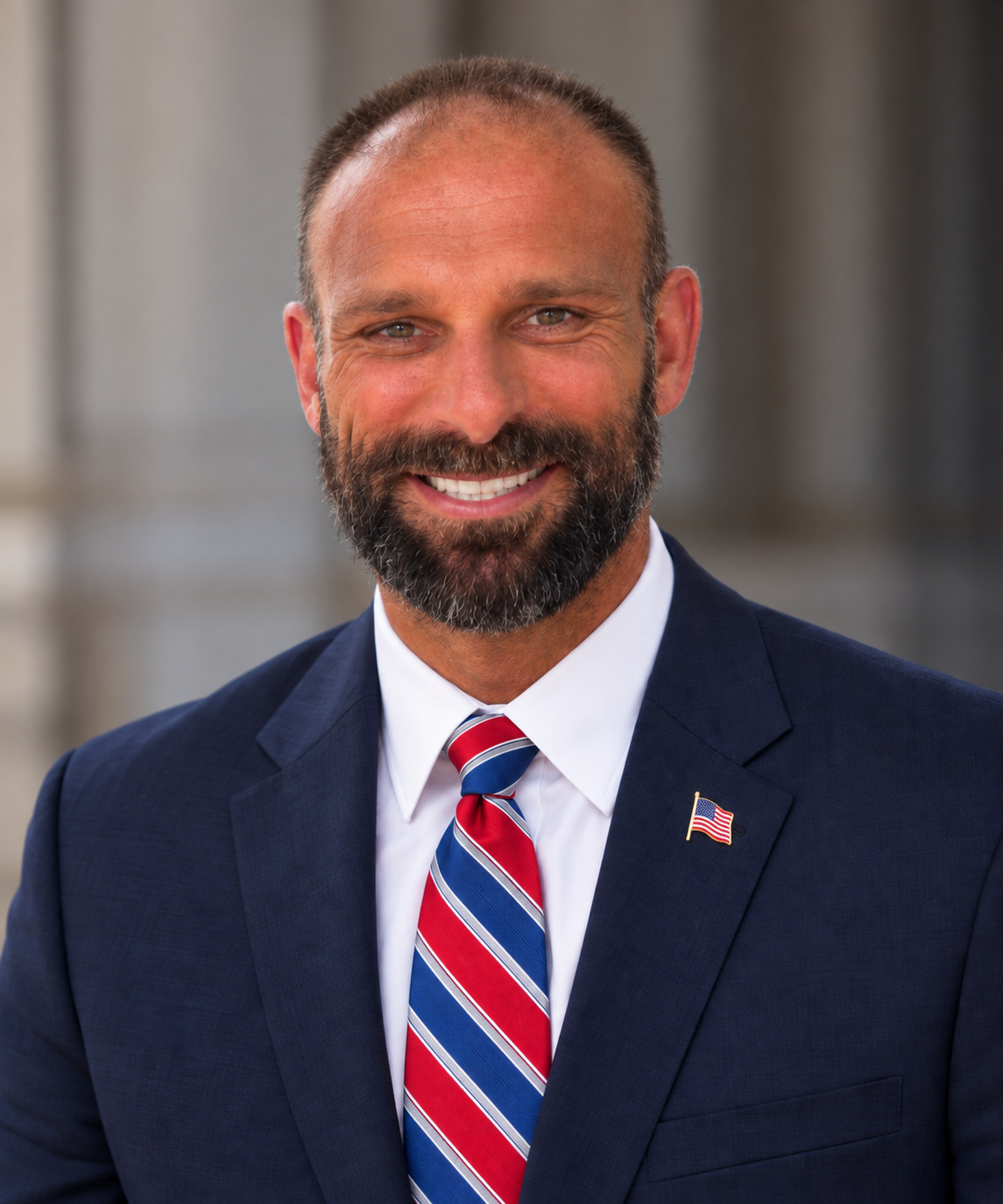 S. Chase Smith wearing a navy suit, red and blue striped tie, and American flag lapel pin